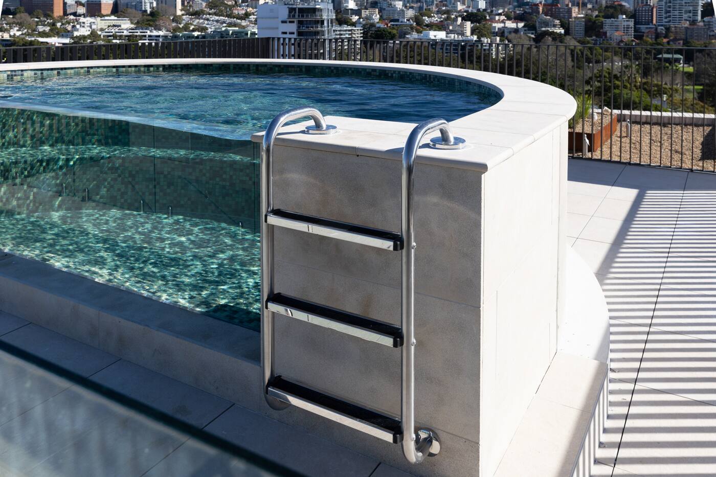 Curved glass end of the rooftop pool over the Sydney skyline