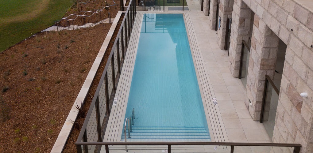 Aerial view along the pool terrace and stone facade, Vela Apartments